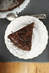 Sliced chocolate cake on wooden table, on light background