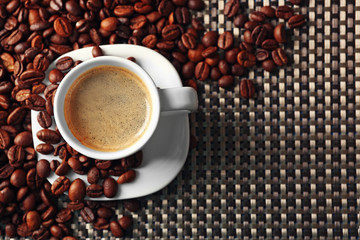 Cup of coffee and coffee grains on dark background
