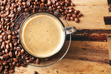 Cup of coffee and coffee grains on wooden table background