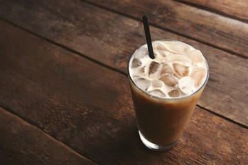 Cup of ice coffee with straw on wooden background