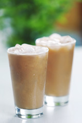 Cups of ice coffee on light blurred background