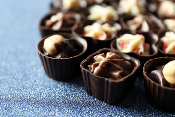 Delicious chocolate candies on blue background, close up