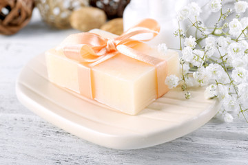 Soap with ribbon on a dish over wooden background, close up