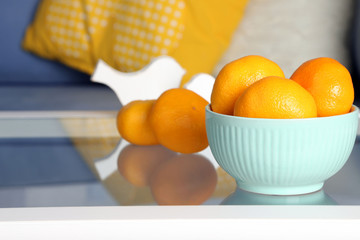 Bowl with fresh tangerines on table in living room, close up