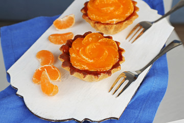 Sweet cakes with tangerines on table, close up