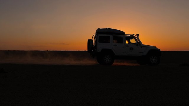 driving off-road car in the sahara desert at sunset