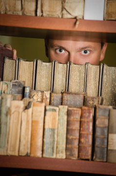 Young adult looking through library bookshelf