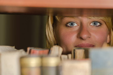 Female student looking through library bookshelf