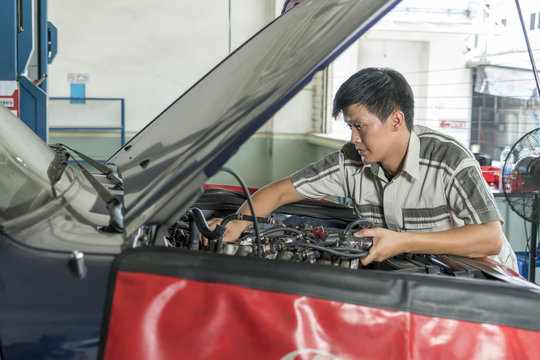 Young mechanic repairing car in service center