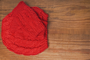 Red knitted cap and mittens on a wooden background.