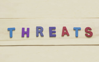 The colorful word "Threats " on wood background : SWOT Concept