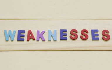 The colorful word "weaknesses" on wood background : SWOT Concept