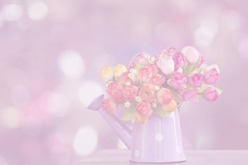 Artificial flowers in watering can with bokeh background