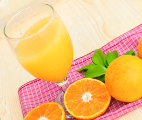 Glass of orange juice with orange slice on soft wooden background