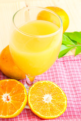 Glass of orange juice with orange slice on soft wooden background