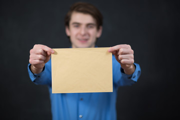 Businessman holding empty paper sheet front of head on blackboar