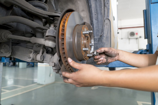 Car mechanic replacing car wheel brake shoes of lifted automobil