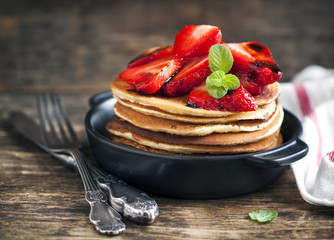 Stack of pancakes with fresh strawberry and balsamic glase in frying pan