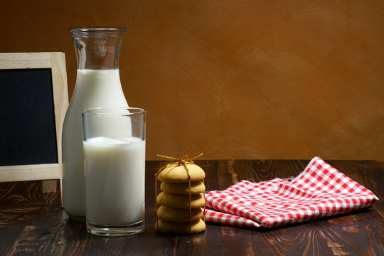 Still life of glass milk on wooden table with cookies