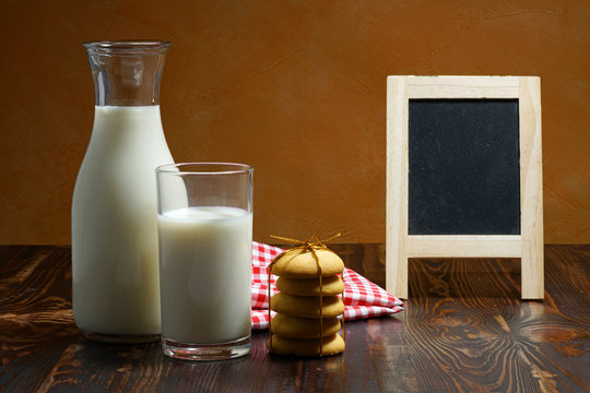 Still life of glass milk on wooden table with cookies
