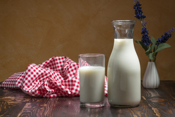 Milk bottle and milk glass put on wooden table.