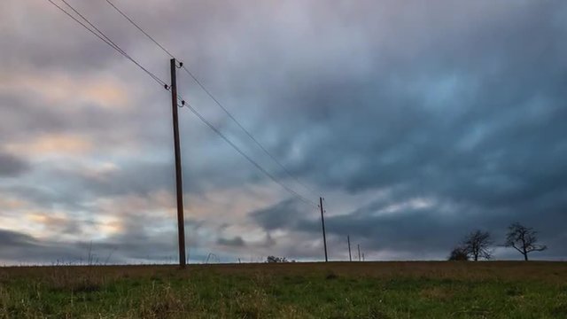 Sonnenuntergang auf einem Feld mit Strommast im Zeitraffer