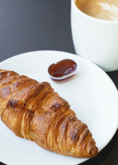 butter croissant and hot latte on black background