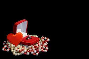 Ring in the red box, red heart and necklace isolated on a black background. Right blank background for text.