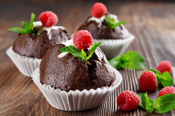 Delicious chocolate cupcakes with berries and fresh mint on wooden table close up