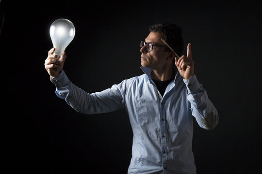 Uomo d'affari tiene in mano una lampada accesa : concetto di idea, creativit&agrave;, motivazione, lavoro , ricerca