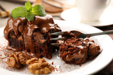 A piece of chocolate cake with walnut and mint on the table, close-up