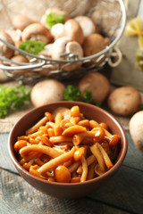 Delicious marinated mushrooms in bowl on wooden background