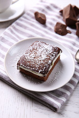 Delicious chocolate brownie on plate on wooden background