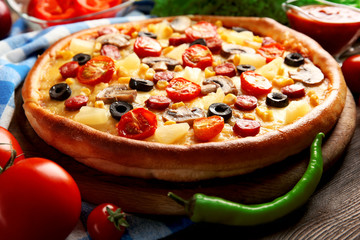 Delicious pizza with vegetables and meat on blue napkin, close-up