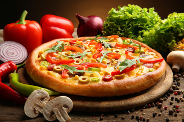 Delicious pizza with vegetables on brown background