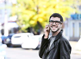 Young man listening to music and walking along the street