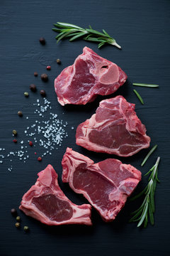 Top view of uncooked T-bone lamb steaks with seasonings