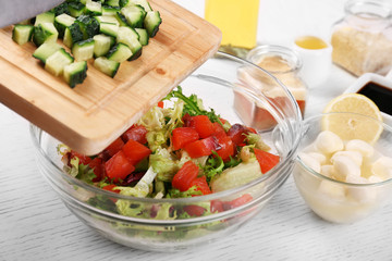 Female hands cutting vegetables for salad, at kitchen