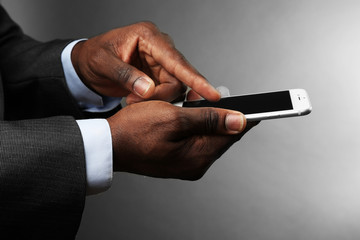 Afro american man holding smartphone on grey background