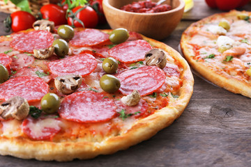 Delicious tasty pizzas with ingredients on table, closeup