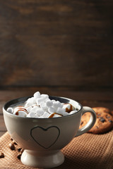 Mug of hot chocolate with marshmallows, on wooden background