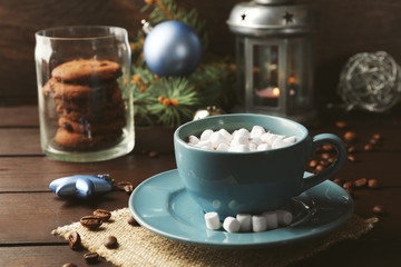 Fototapeta na wymiar Mug of hot chocolate with marshmallows, fir tree branch on wooden background