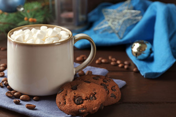 Mug of hot chocolate with marshmallows, fir tree branch on wooden background
