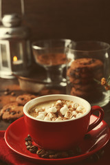 Mug of hot chocolate with marshmallows, fir tree branch on wooden background