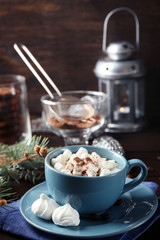 Mug of hot chocolate with marshmallows, fir tree branch on wooden background