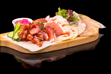 Sliced prosciutto, bacon and other deli meats lie on the board.