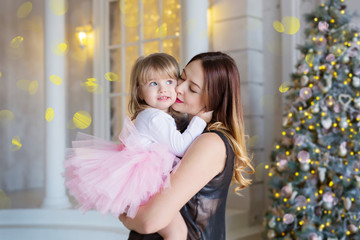 Mother with daughter on hands in the Christmas atmosphere