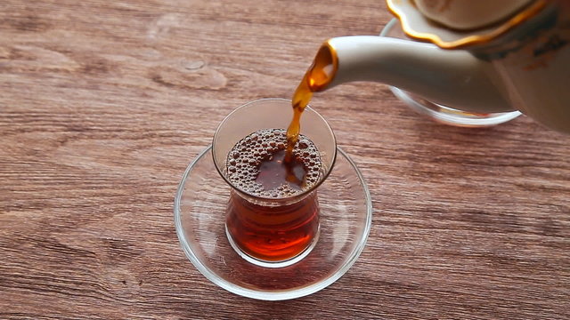 Pouring Tea Into A Cup On A Wooden Table