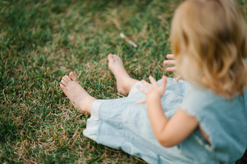 Portrait of a child sitting on grass on summer sunset afternoon and playing
