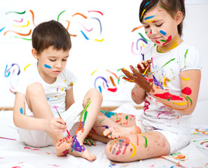Cute boy and girl playing with paints